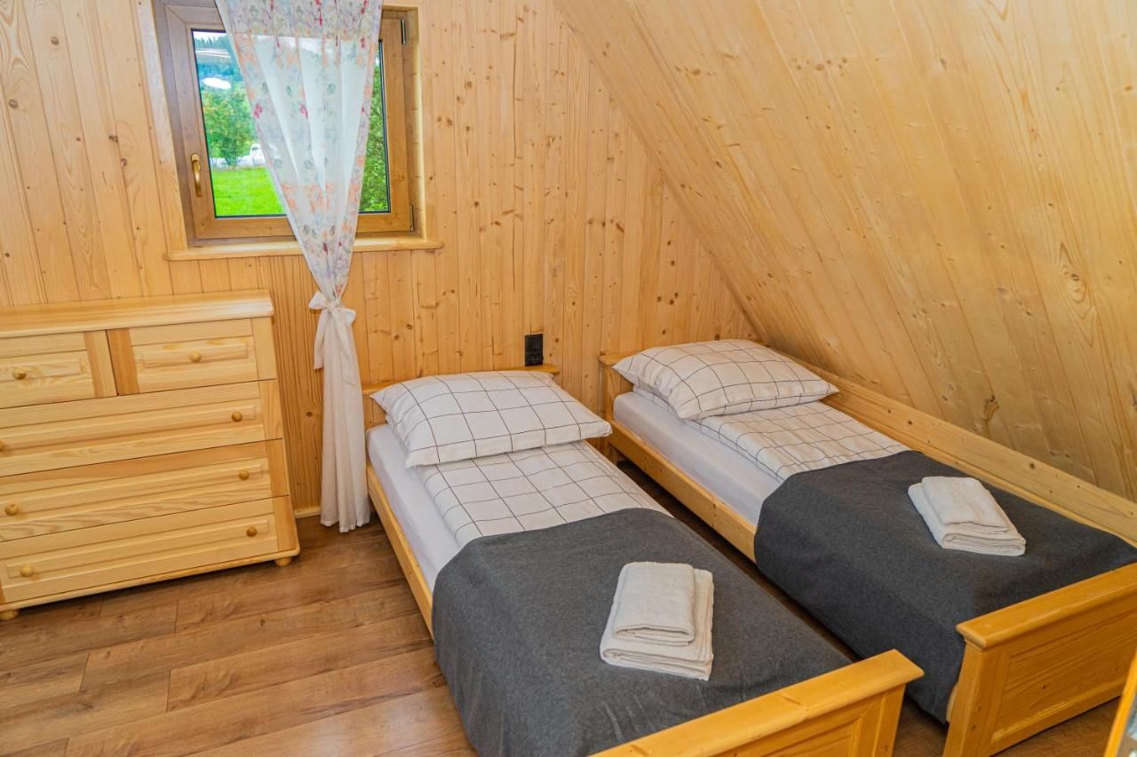 Sypialnia z dwoma pojedynczymi łóżkami pod drewnianym skosem